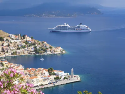 Ein Kreuzfahrtschiff fährt entlang einer Stadt am Wasser