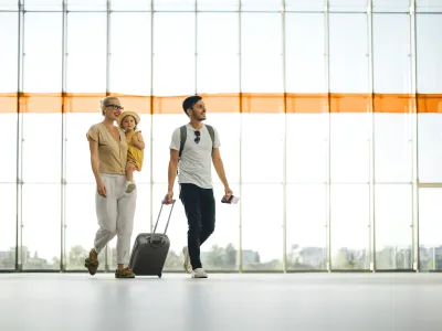 Eine Familie geht mit einem Koffer im Flughafen herum.