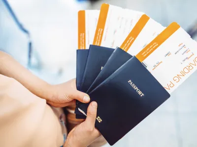 Eine Person hält drei Reisepässe mitsamt Ticket aufgefächert in den Händen.