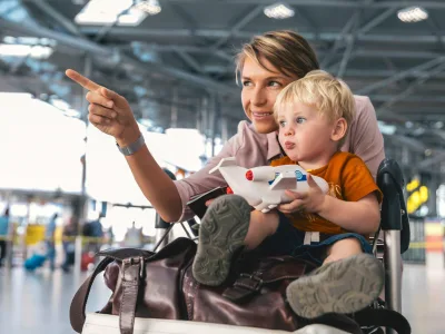 Eine Mutter mit ihrem Kind an einem Flughafen. Die Mutter zeigt auf etwas, das Kind schaut hin.