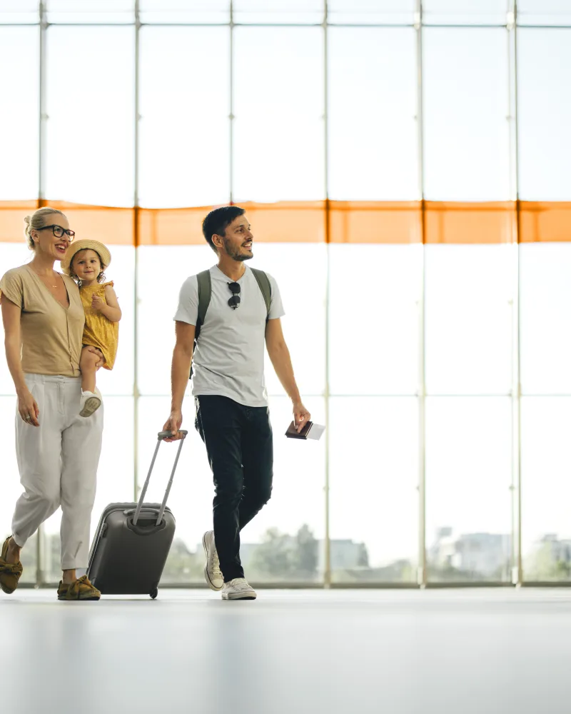 Eine Familie geht mit einem Koffer im Flughafen herum.